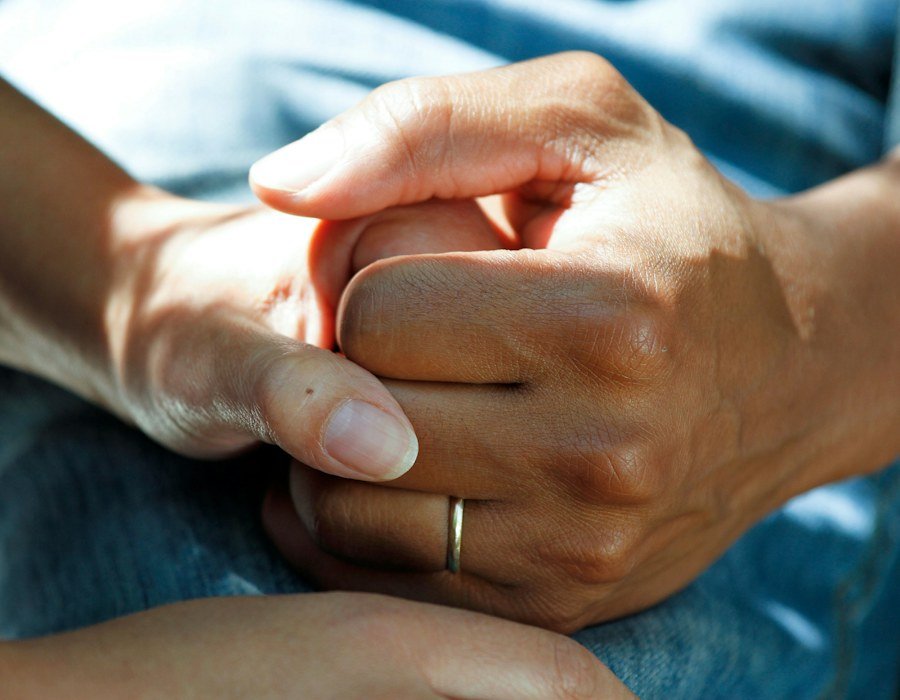 A caregiver gently holding a patient's hand